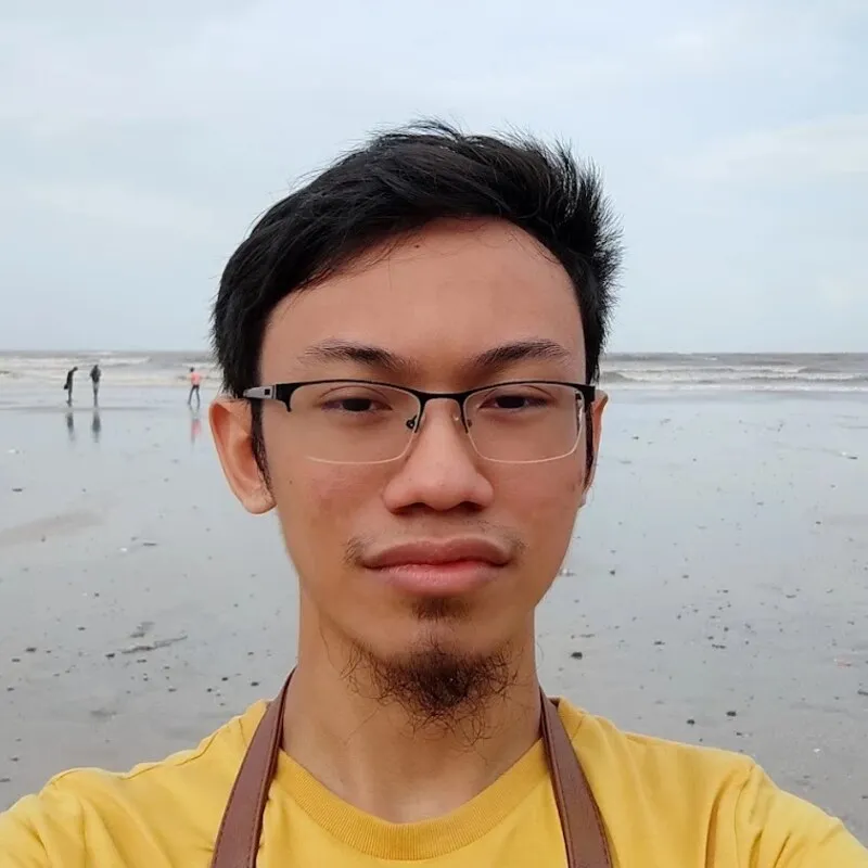 Elham Nazif, smiling slightly, in a yellow T-shirt on a beach